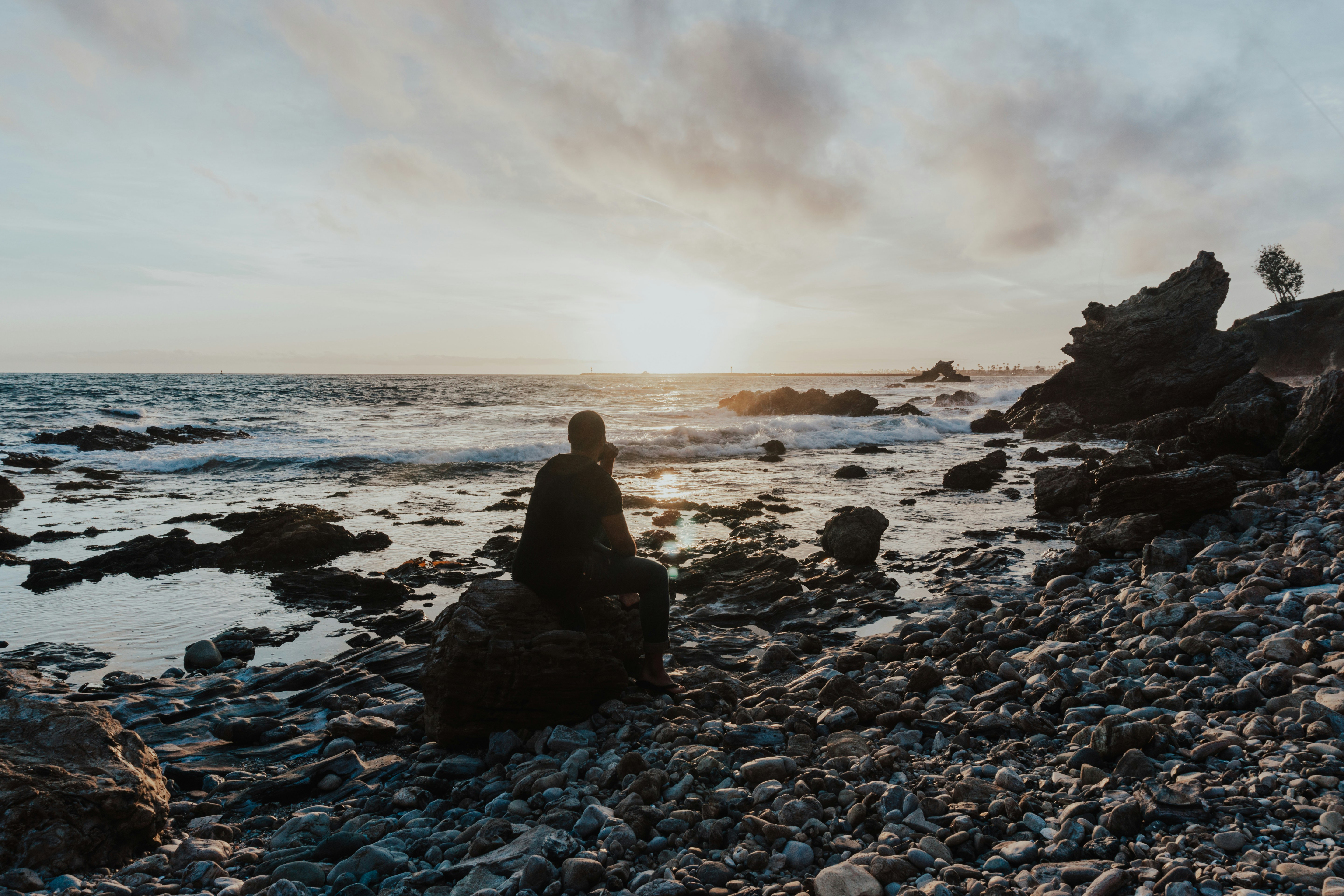 person sitting on rock near sea during daytime